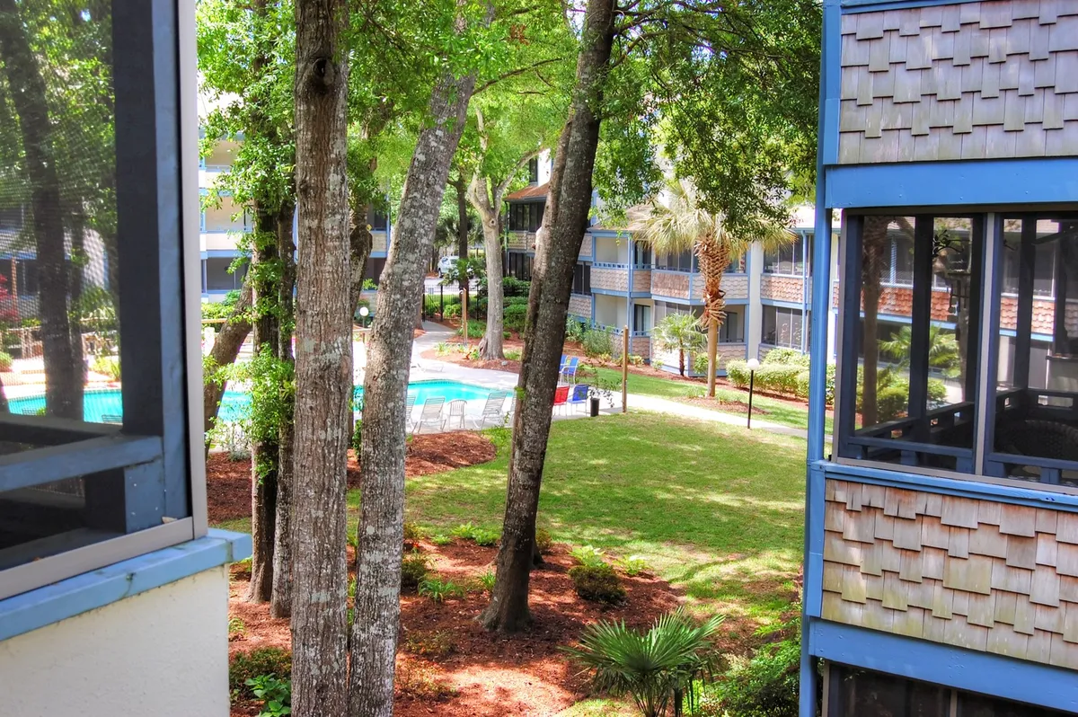 The hero image features an inviting outdoor swimming pool surrounded by a lush green lawn and mature trees, with the Summertree Village condo buildings in the background. The setting suggests opportunities for swimming, sunbathing, and relaxing in a cheerful, family-friendly atmosphere, enhanced by the possibility of sunset swims and outdoor activities like poolside barbecues or morning yoga.
